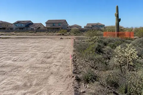 Excavator opening a vacant residential parcel on the desert edge of Surprise with the Hieroglyphic Mountains behind